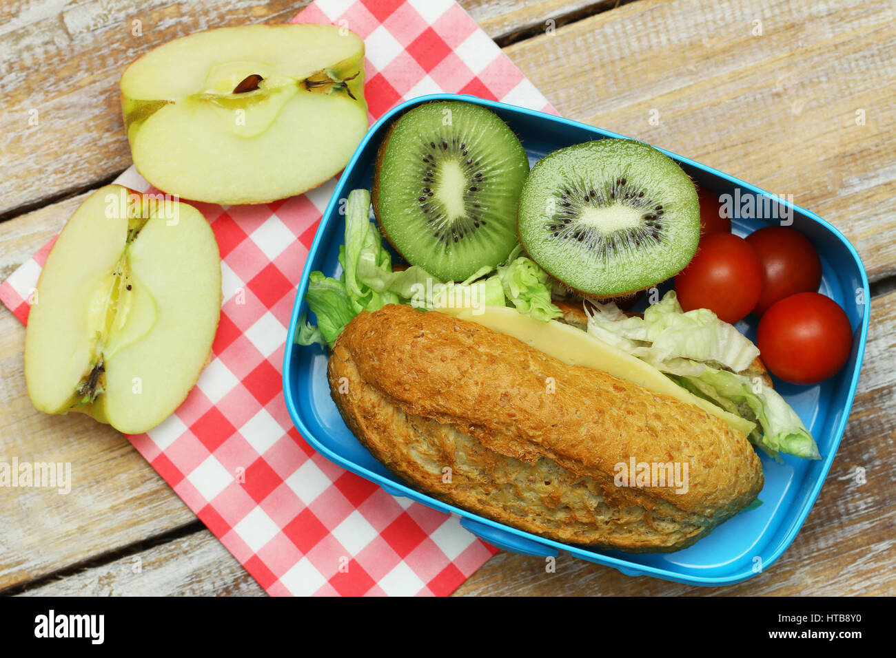 Un sano pranzo al sacco contenente formaggio marrone sandwich, pomodorini e frutta fresca Foto Stock