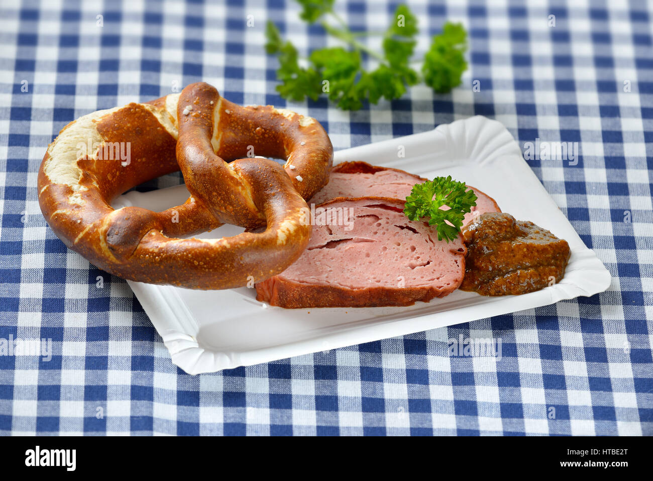 Bavarese di cibo da asporto: Fette di polpettone caldo con senape dolce e un pretzel su un piatto di carta Foto Stock