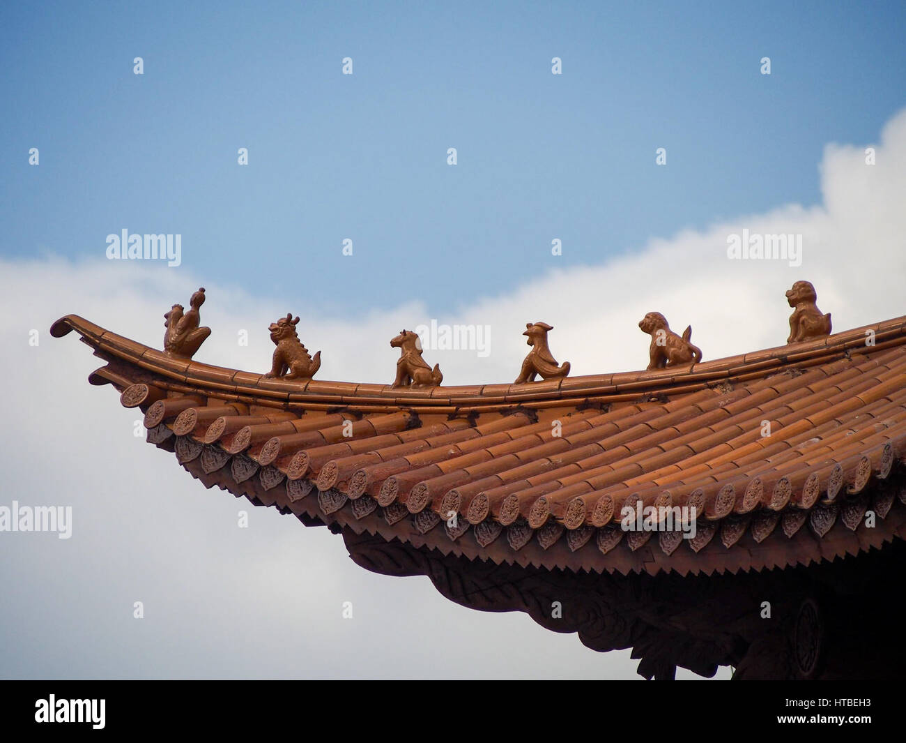 Le figure a guardia della parte superiore di un'arancia piastrellato sul tetto tradizionale in Cina. Foto Stock