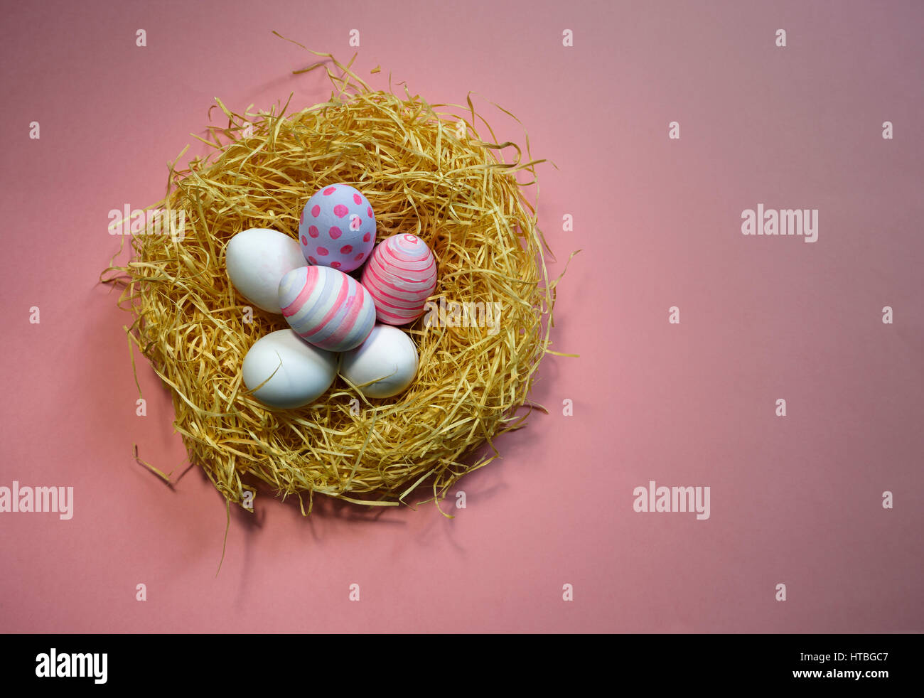 Vintage colorate uova di pasqua nel nido su sfondo rosa. Foto Stock