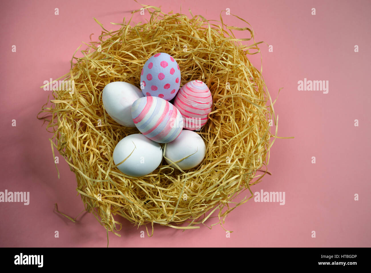 Vintage colorate uova di pasqua nel nido su sfondo rosa. Foto Stock