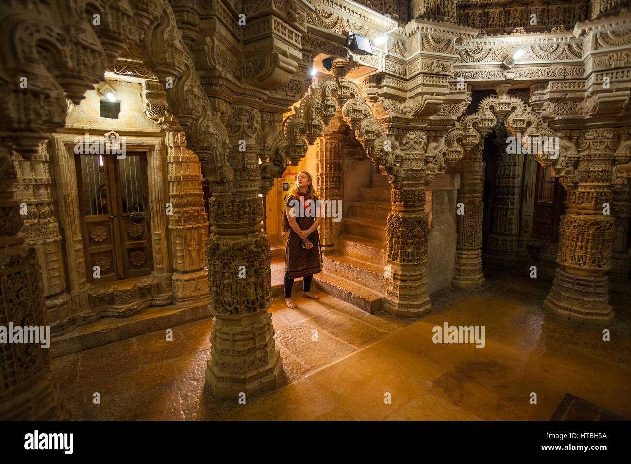 Una donna guarda la sorprendente scultura in pietra all'interno del tempio Jain in Jaisalmer Fort, Jaisalmer, Rajashan, India. Foto Stock