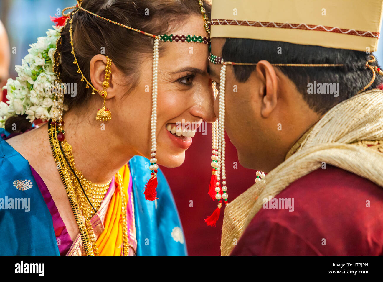 La felice sposa e lo sposo a un matrimonio indiano cercando in uno anothers gli occhi con la loro fronte toccando. Foto Stock