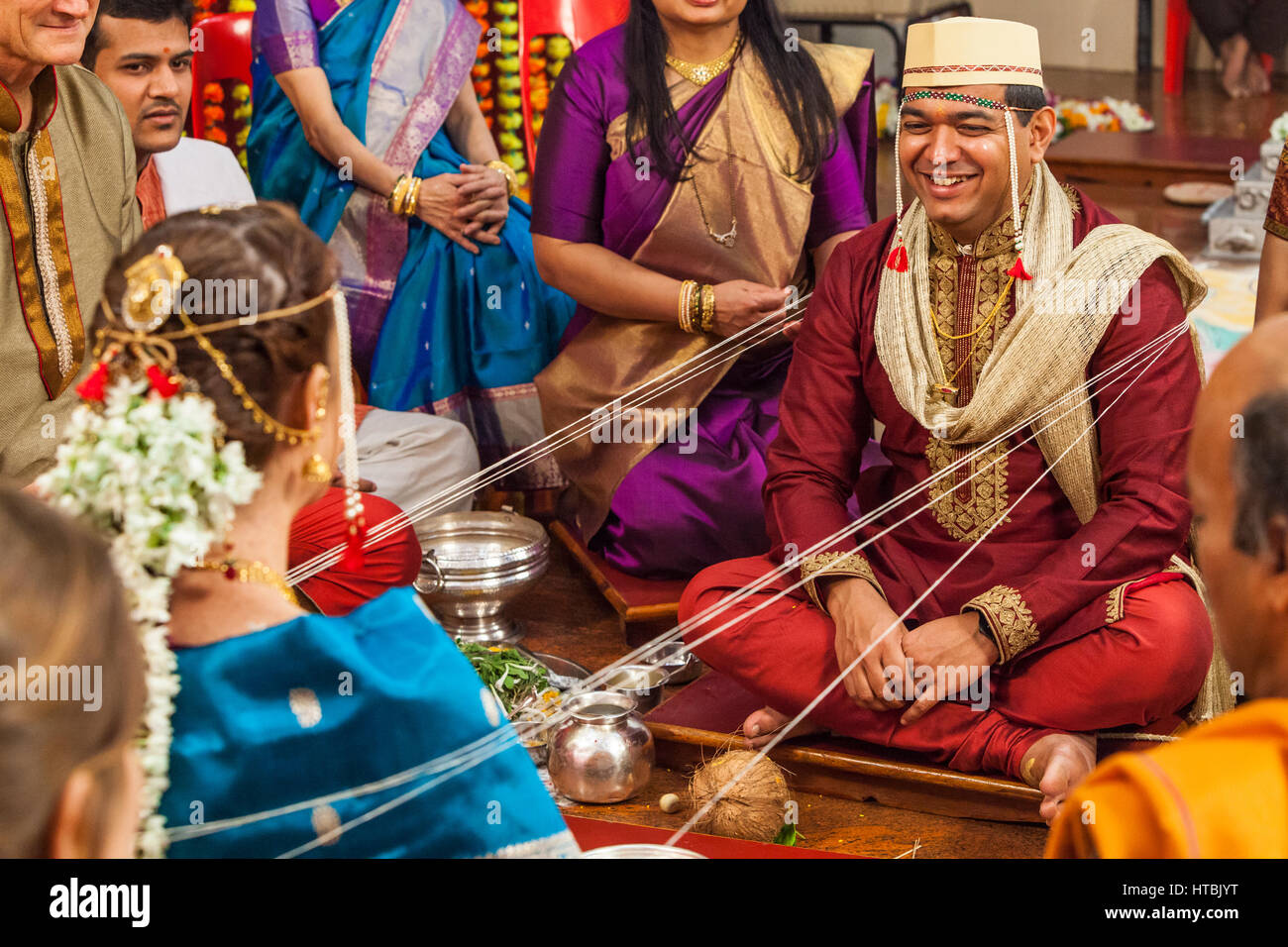 Il govern sorridente durante una portrion del suo Hindu / Indian nozze dove la sposa e lo sposo sono legati insieme e avvolto con la stringa che viene passata Foto Stock