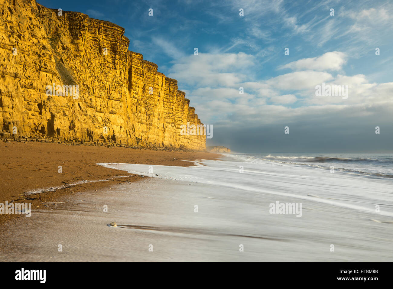 Onde che si infrangono sulla spiaggia al di sotto di East Cliff, West Bay, Jurassic Coast, Dorset, England, Regno Unito Foto Stock