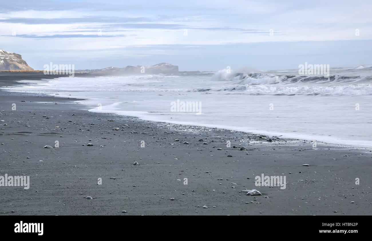 Lava nera spiaggia con spuma le onde a VIK, Islanda, sulla giornata invernale con moody del cielo della sera e le onde che si infrangono Foto Stock