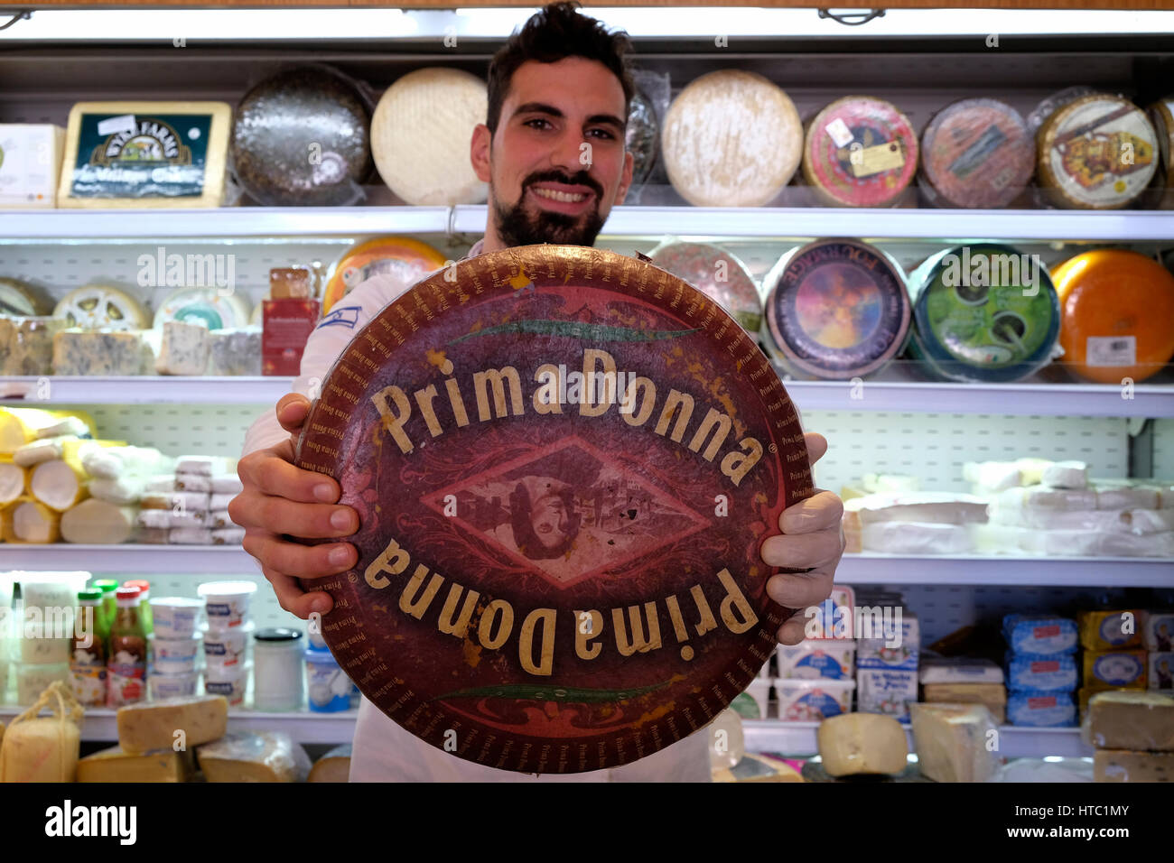 Un venditore detiene una ruota di formaggio prima Donna olandese presso il negozio di formaggio Basher Fromagerie a Mahane o Machane Yehuda mercato spesso chiamato 'The Shuk', un mercato all'aperto, a Gerusalemme ovest, Israele Foto Stock