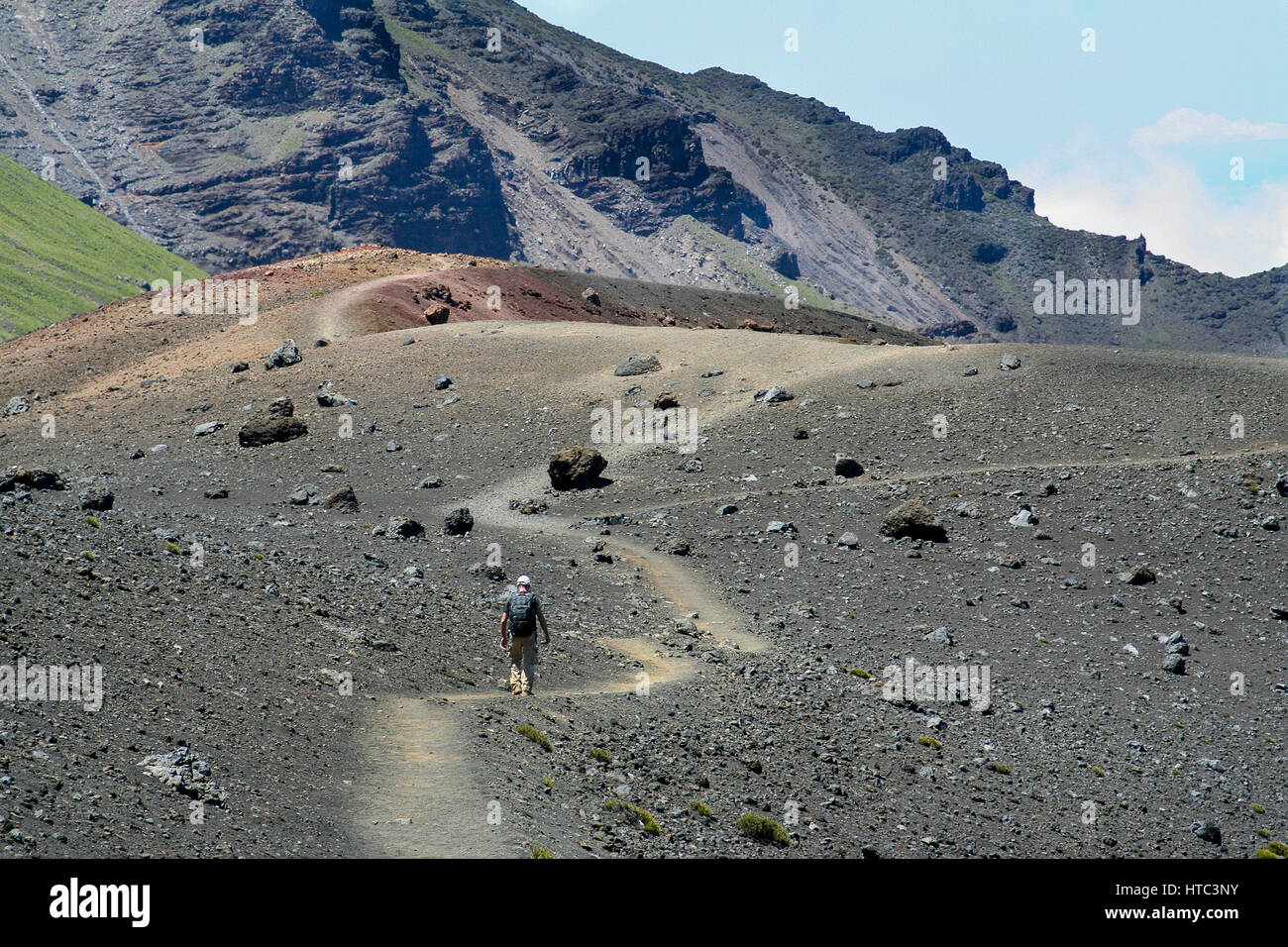 Un uomo cammina lungo un sentiero in Haleakalā verso un cratere. Foto Stock