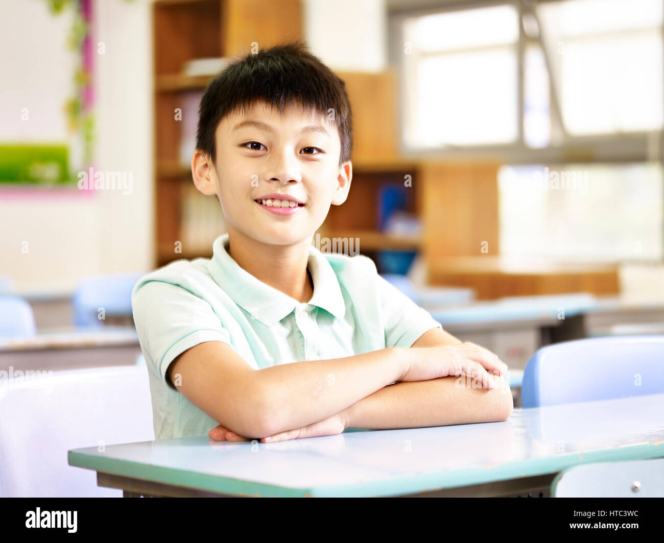 Ritratto di un undici anni di asiatici scuola elementare studente seduto in aula. Foto Stock