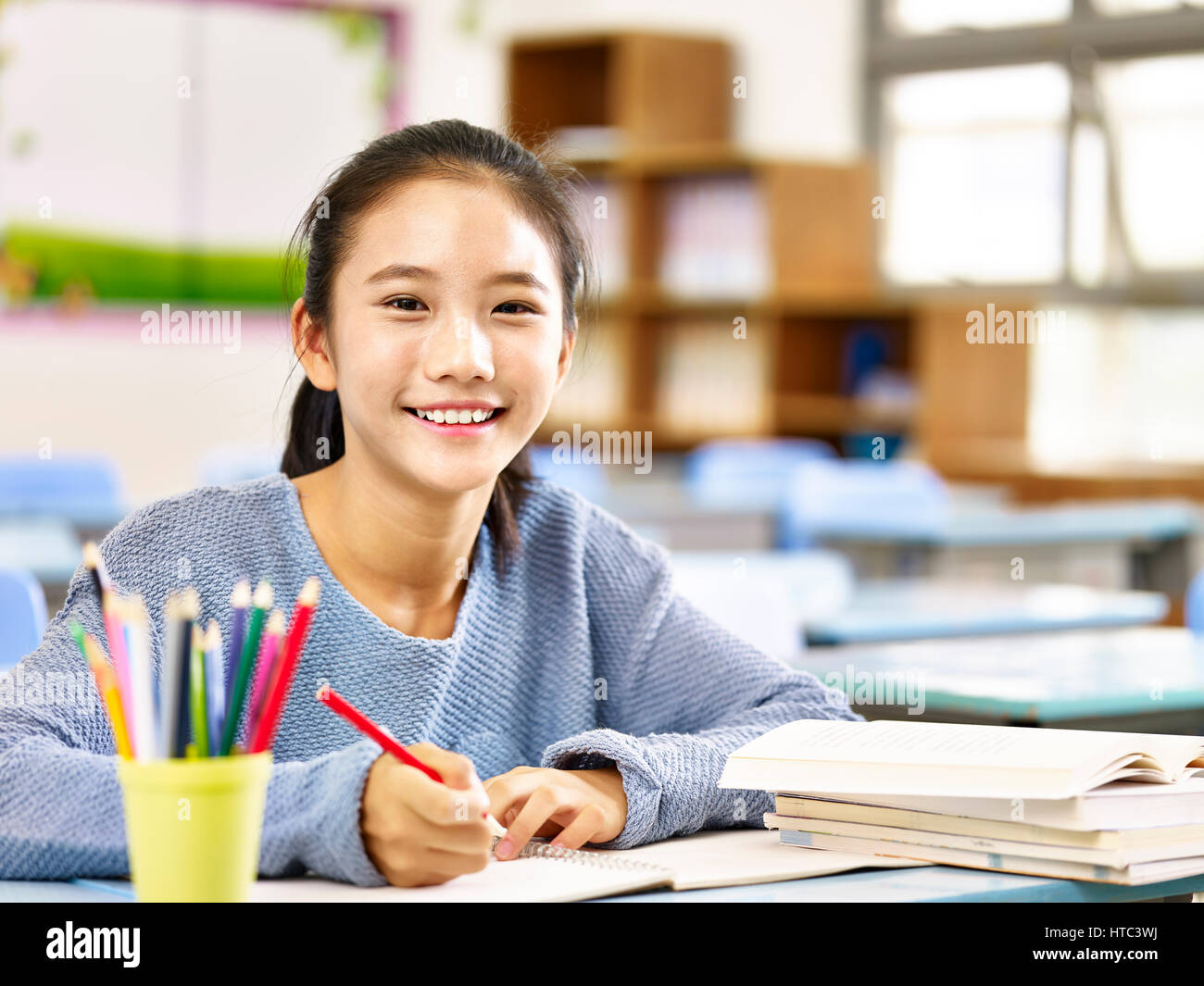 Felice asiatici scuola elementare studente in aula guardando la telecamera sorridendo, Foto Stock