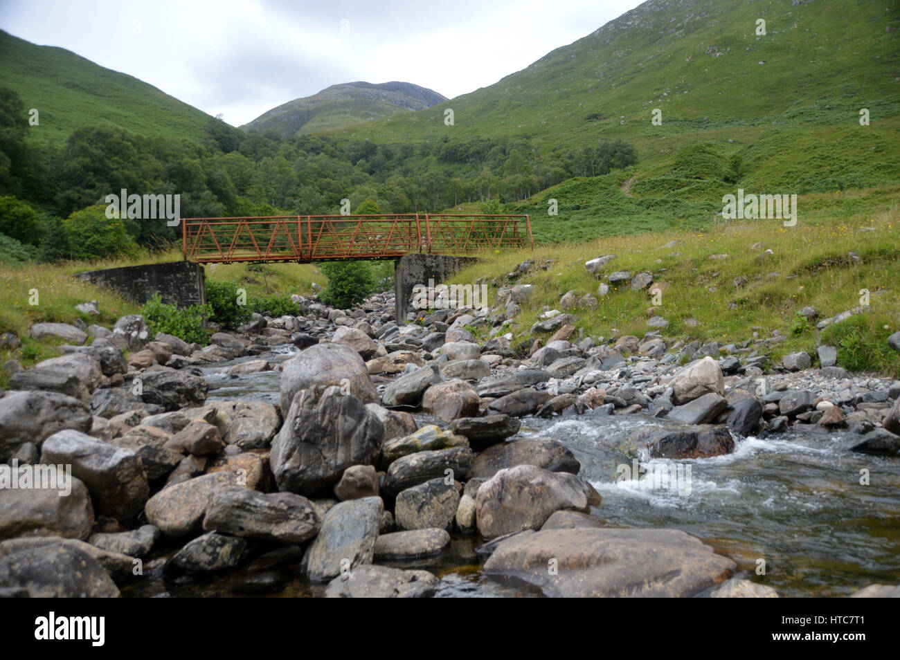 Un arrugginito ponte Allt Utha a Achad un' Ghlinne Bothy in Glen Arnisdale con la montagna scozzese Corbett Beinn nan Caorach in background, Foto Stock