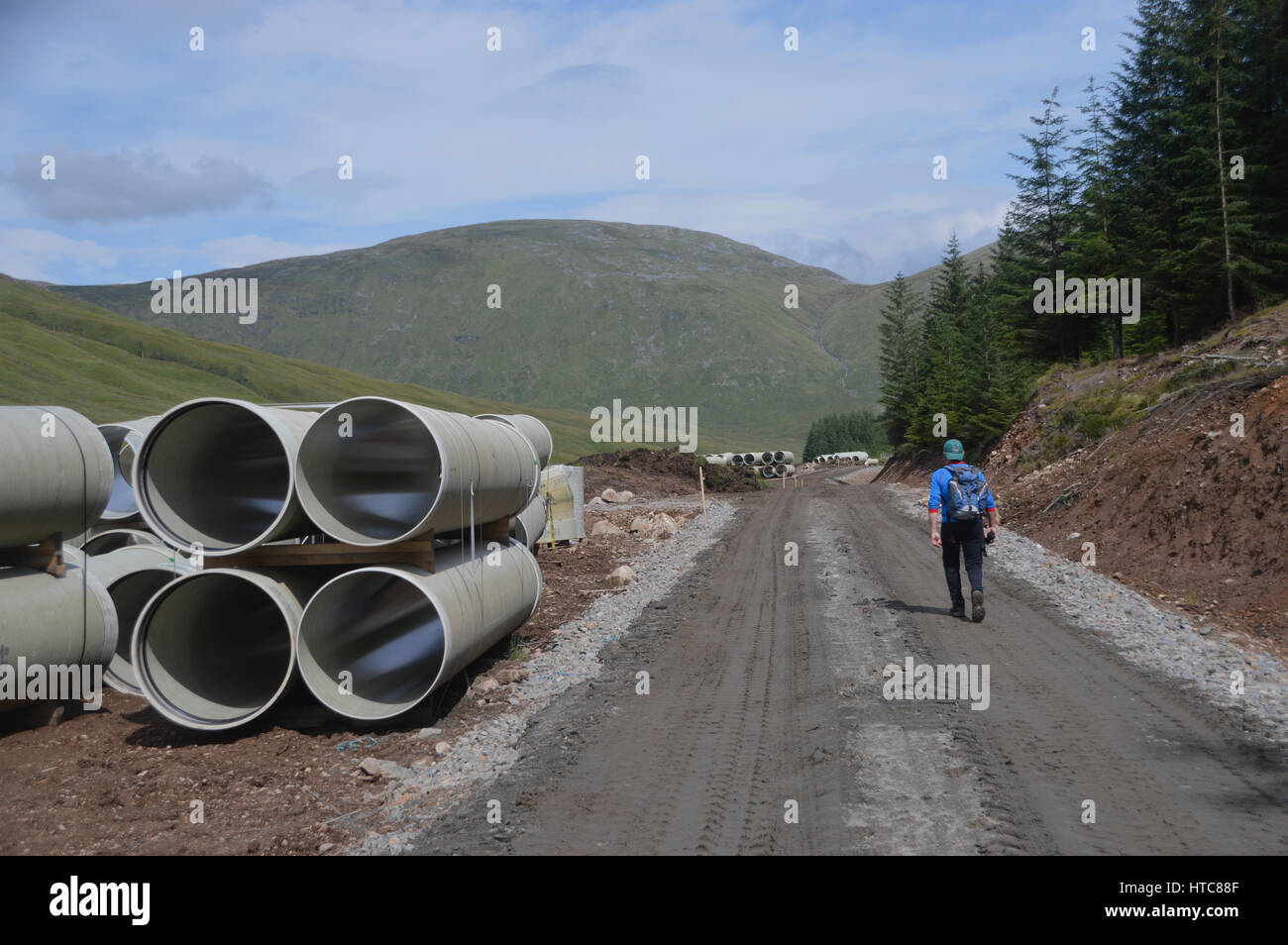 Un solitario Hillwalker maschio in Gleann Cia-aig a piedi attraverso Constuction sito per la montagna scozzese Corbett Meall na h-Eilde nelle Highlands Scozzesi. Foto Stock