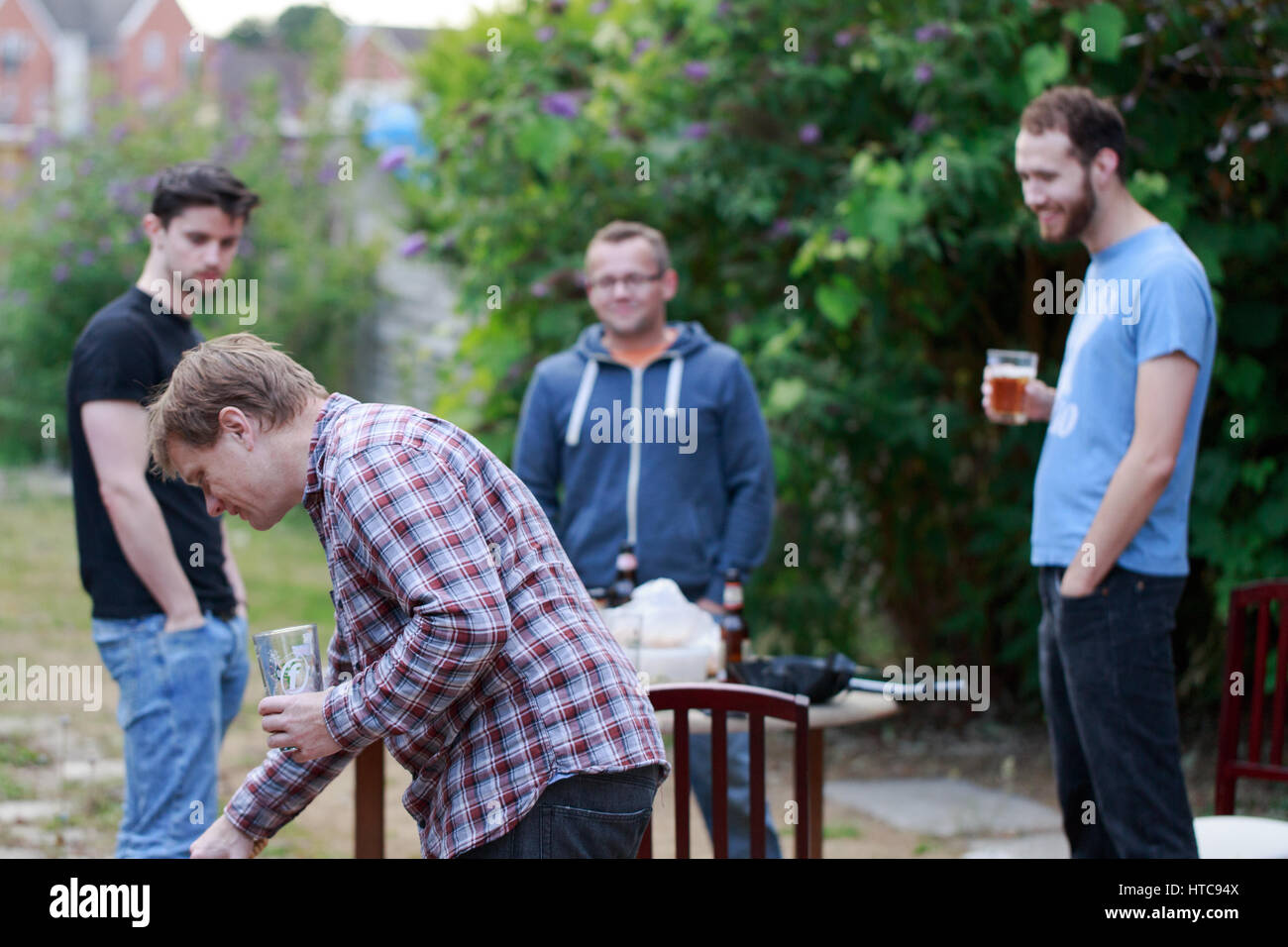 Gruppo di giovane uomo riunione amici dopo il lavoro per bere birra, barbecue in giardino nel cortile a Woking, in Inghilterra. Composizione orizzontale Foto Stock