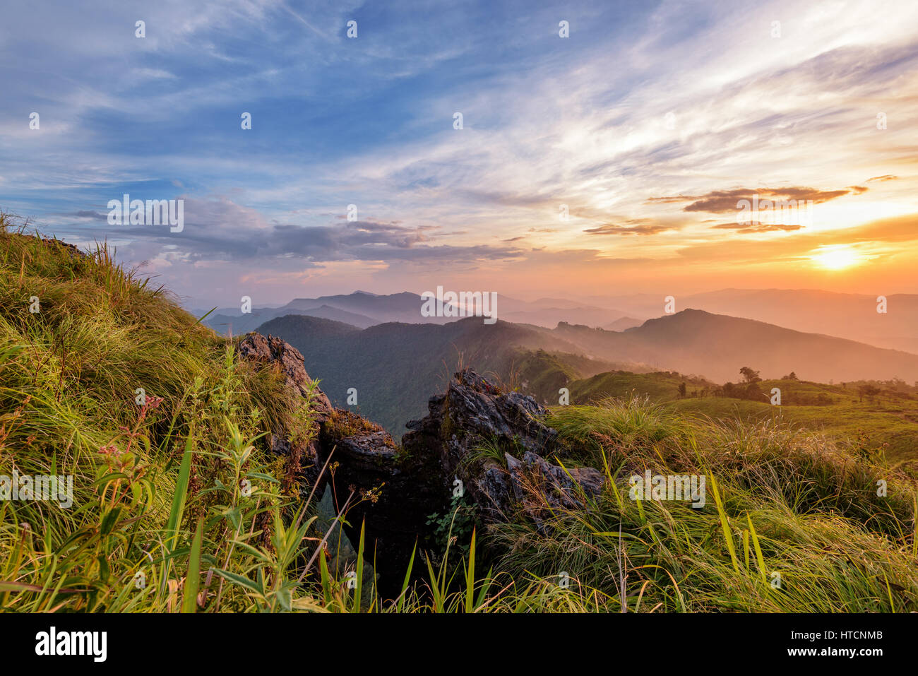 Bellissimo paesaggio natura sui picchi di montagna con sun cloud nebbia e colori luminosi del cielo e la luce del sole durante il tramonto in inverno a Viewpoint Phu Chi fa Foto Stock