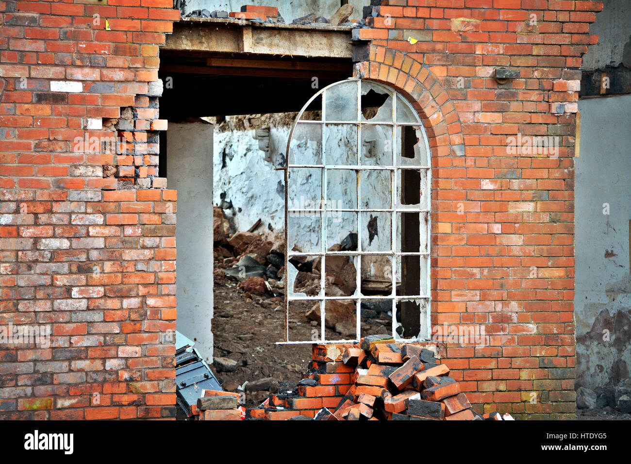 Un Semi demolito edificio di mattoni con una finestra ancora metà nel suo telaio Foto Stock