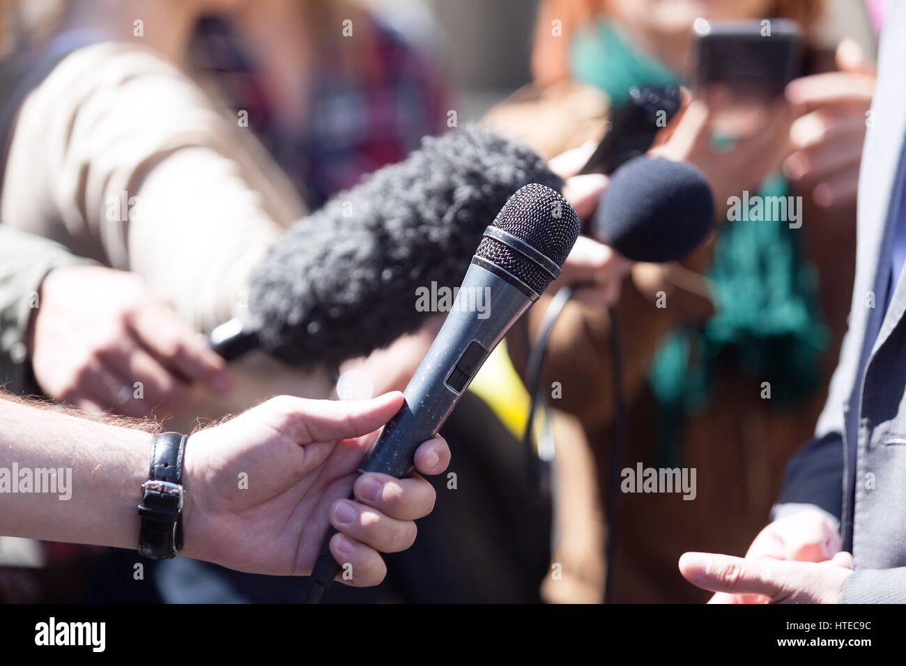 Reporters holding microfoni supporti conduttore intervista Foto Stock