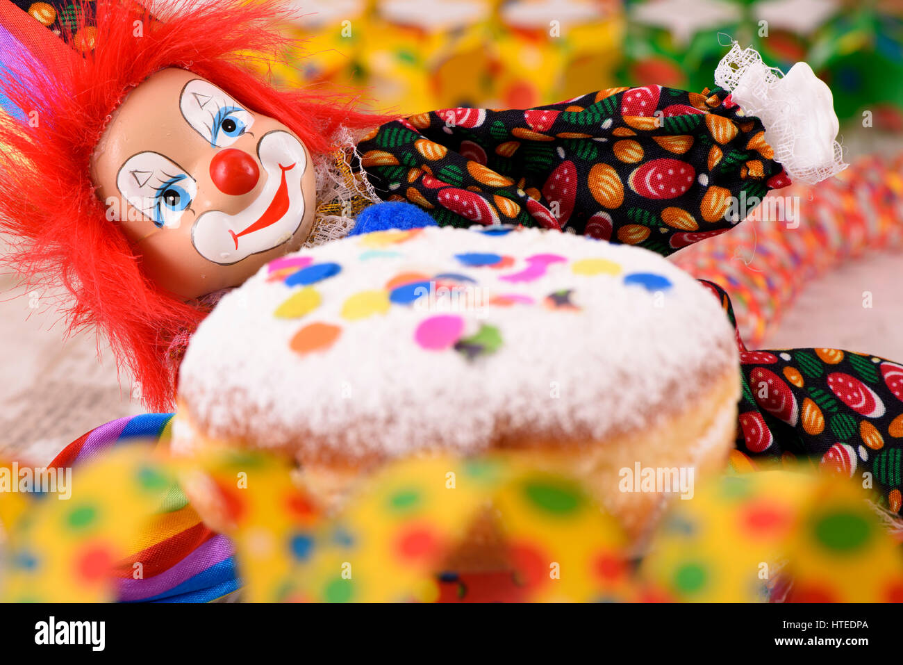 Il pagliaccio con i capelli rossi e il dolce a ciambella a carnevale Foto Stock