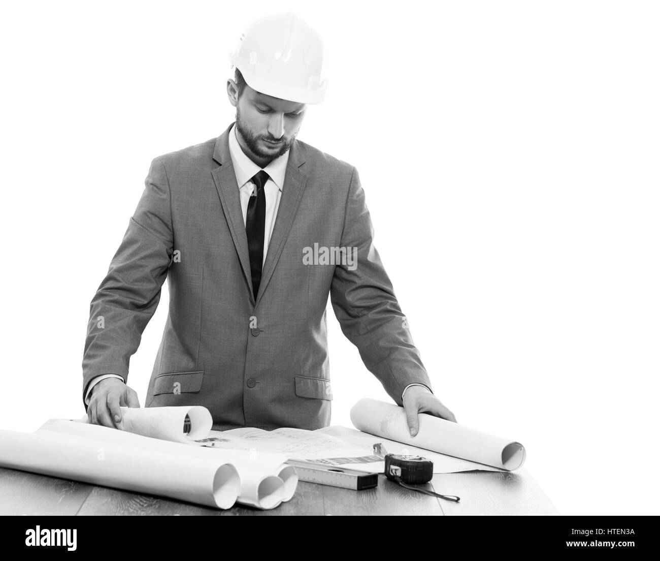 Progetti di costruzione. Girato in bianco e nero di un professionista maschio maturo architetto elaborare piani di costruzione copyspace isolato su bianco tecnico delle costruzioni Foto Stock
