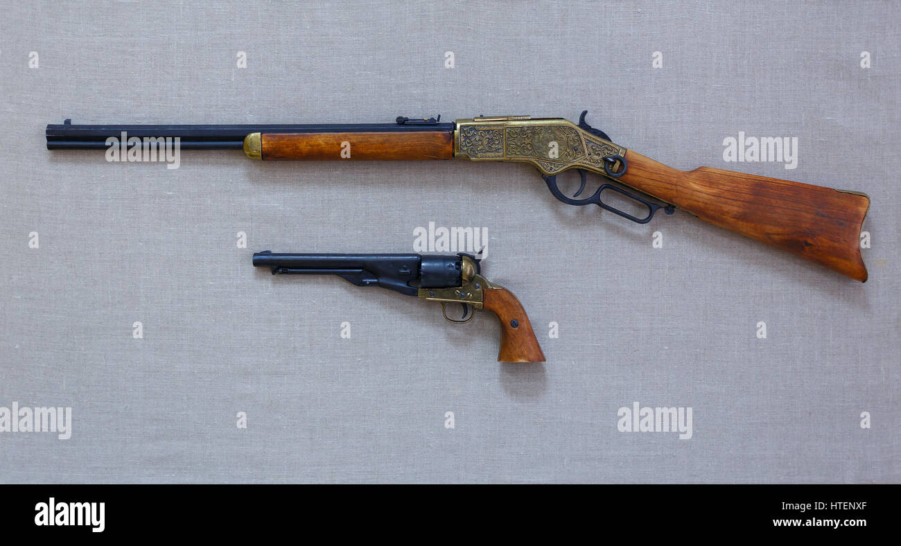 Il vecchio fucile e una pistola con legno e pezzi di metallo sono sul tessuto in background. Foto Stock