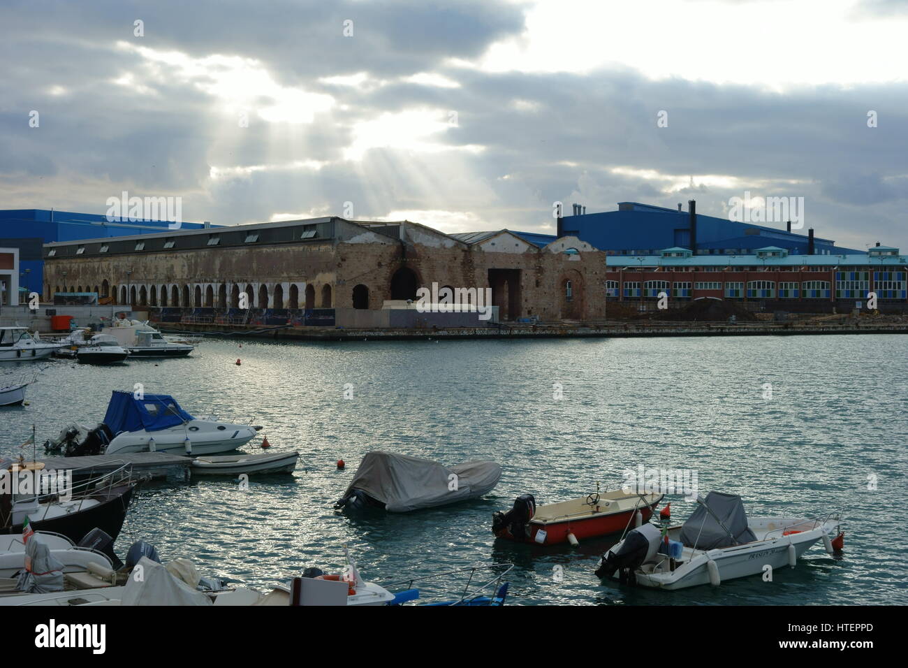 Sunray di luce attraverso le nuvole su edifici industriali - Livorno docks, porto industriale, Toscana, Italia, Europa - paesaggio urbano serie Foto Stock