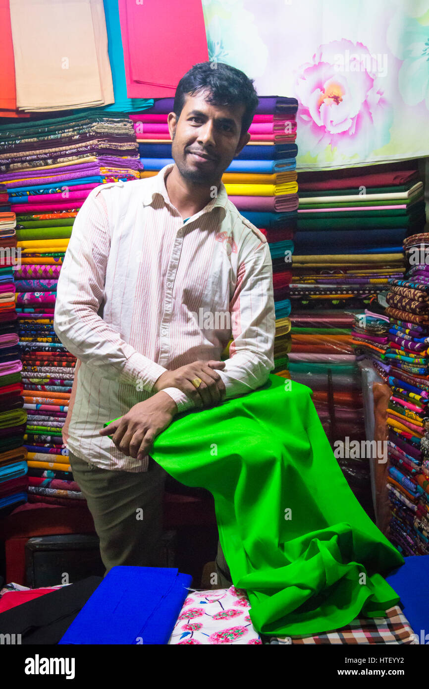 CHITTAGONG, BANGLADESH - Febbraio 2017: l'uomo con un piccolo negozio di tessuti e di indumenti nella centrale mercato bazar a Chittagong, Bangladesh Foto Stock