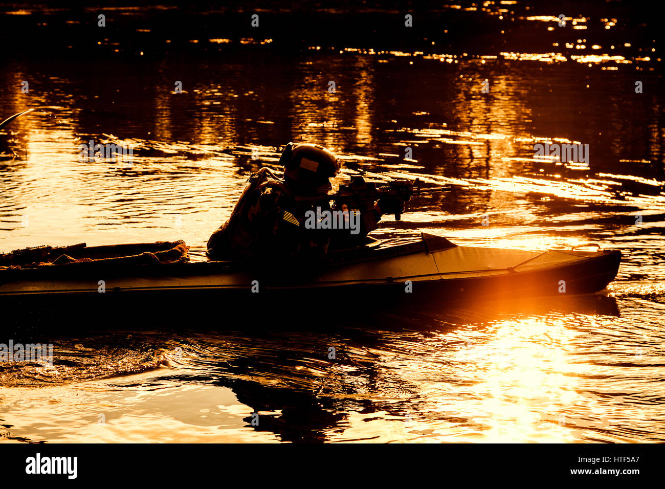 Silhouette di forze speciali uomo con fucile esercito in kayak. Barca con calma in movimento attraverso il fiume, diversivo mission, Tramonto Tramonto Foto Stock