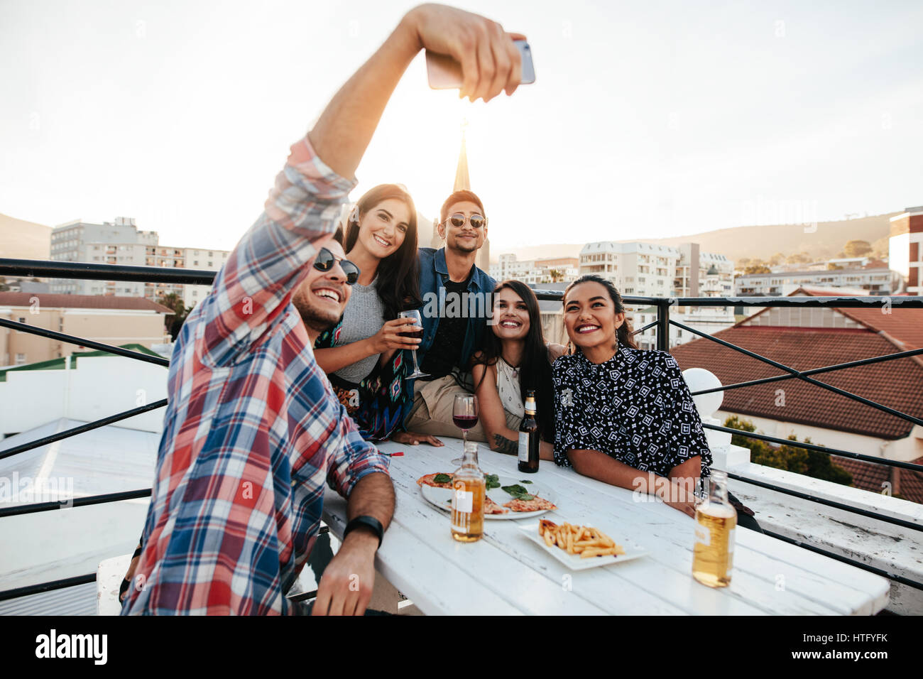 Gruppo di amici avente una parte sul tetto facendo una selfie. Felice e gioiosa giovani prendendo ritratto di auto durante la festa sul tetto. Foto Stock