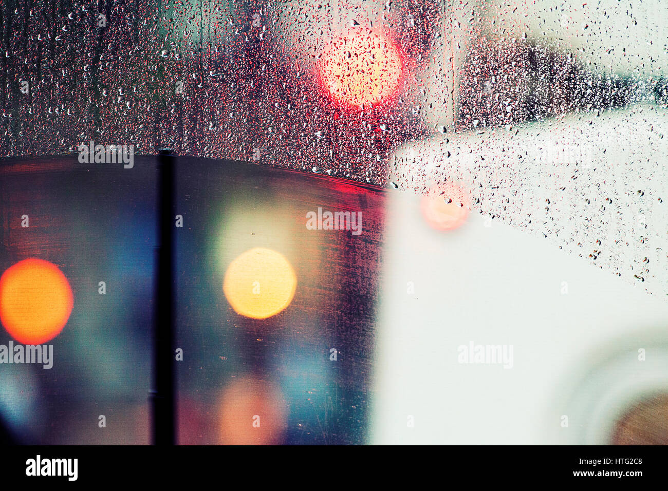 Bokeh luci e gocce di pioggia su una finestra di bus. Foto Stock