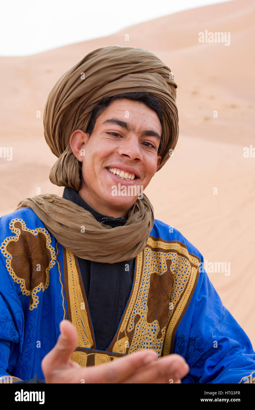 Un nomade uomo berbero con i bracci aperti accoglie i turisti del deserto del Sahara, Marocco Foto Stock