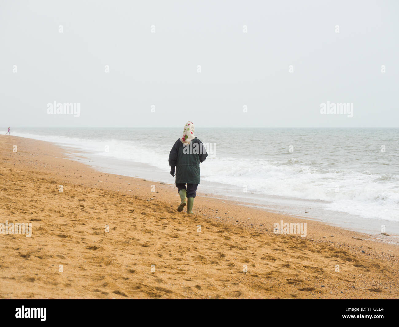 Burton Bradstock, Dorset, Regno Unito, 11 marzo 2017, una donna con la possibilità di passeggiare lungo la spiaggia Burton Bradstock spiaggia su un vago e nebbioso giorno nel West Dorset st Burton Bradstock beach, Dorset, Regno Unito. © Dan Tucker/Alamy Live News Foto Stock