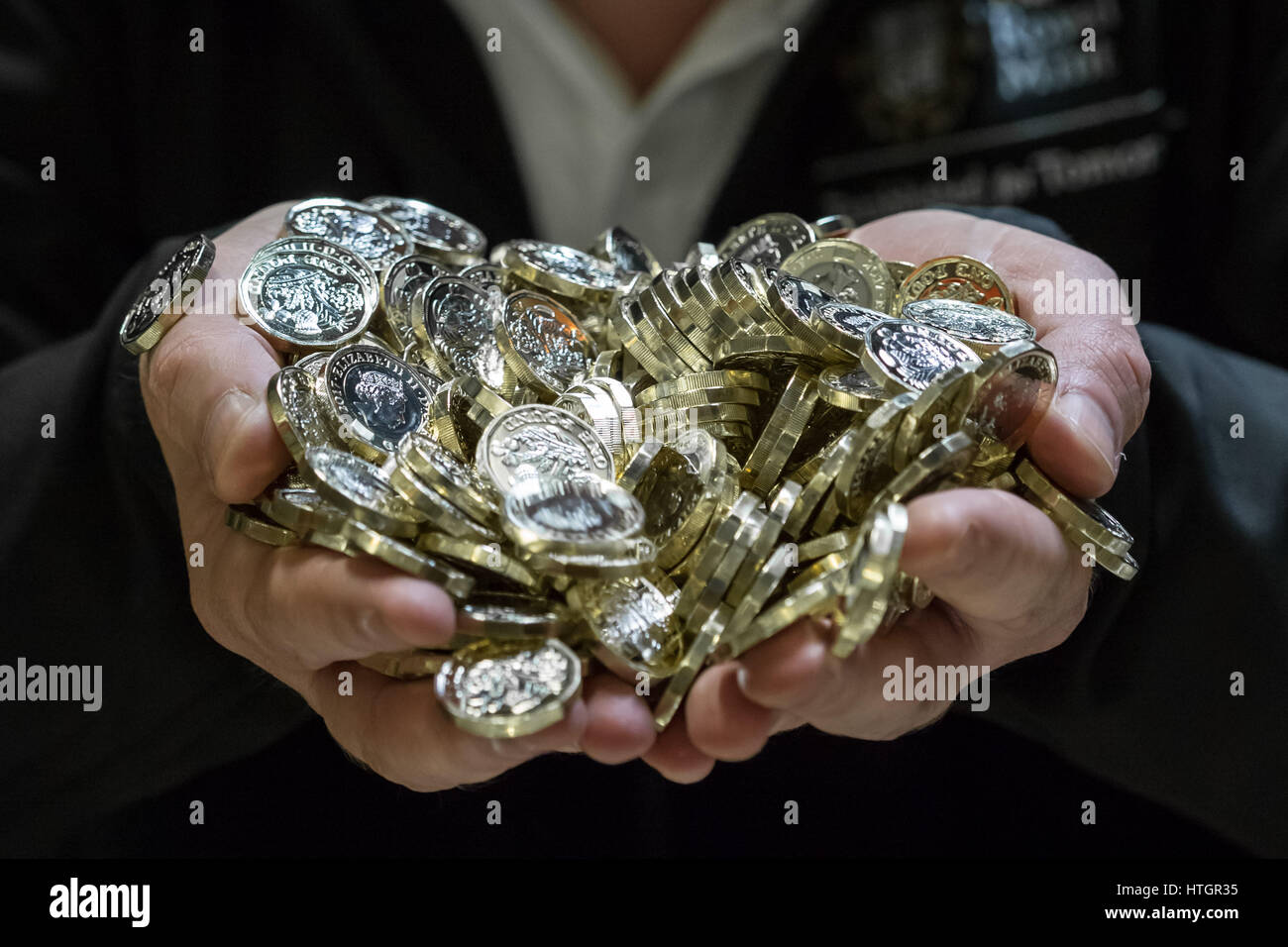 Llantrisant, nel Galles del Sud, Regno Unito. Il 14 marzo 2017. Scott Kuperus, 40, valuta la sicurezza e esperto tecnico presso il Royal Mint per 9 anni. Tenendo un lotto di appena premuto £1 monete. © Guy Corbishley/Alamy Live News Foto Stock