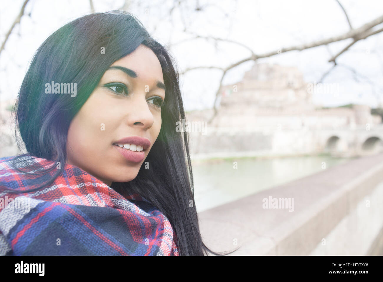 Giovane bella gara di misto donna con espressione malinconica, guardando oltre a Roma, in Italia con Sant Angelo il castello e il fiume Tevere in background di un Foto Stock