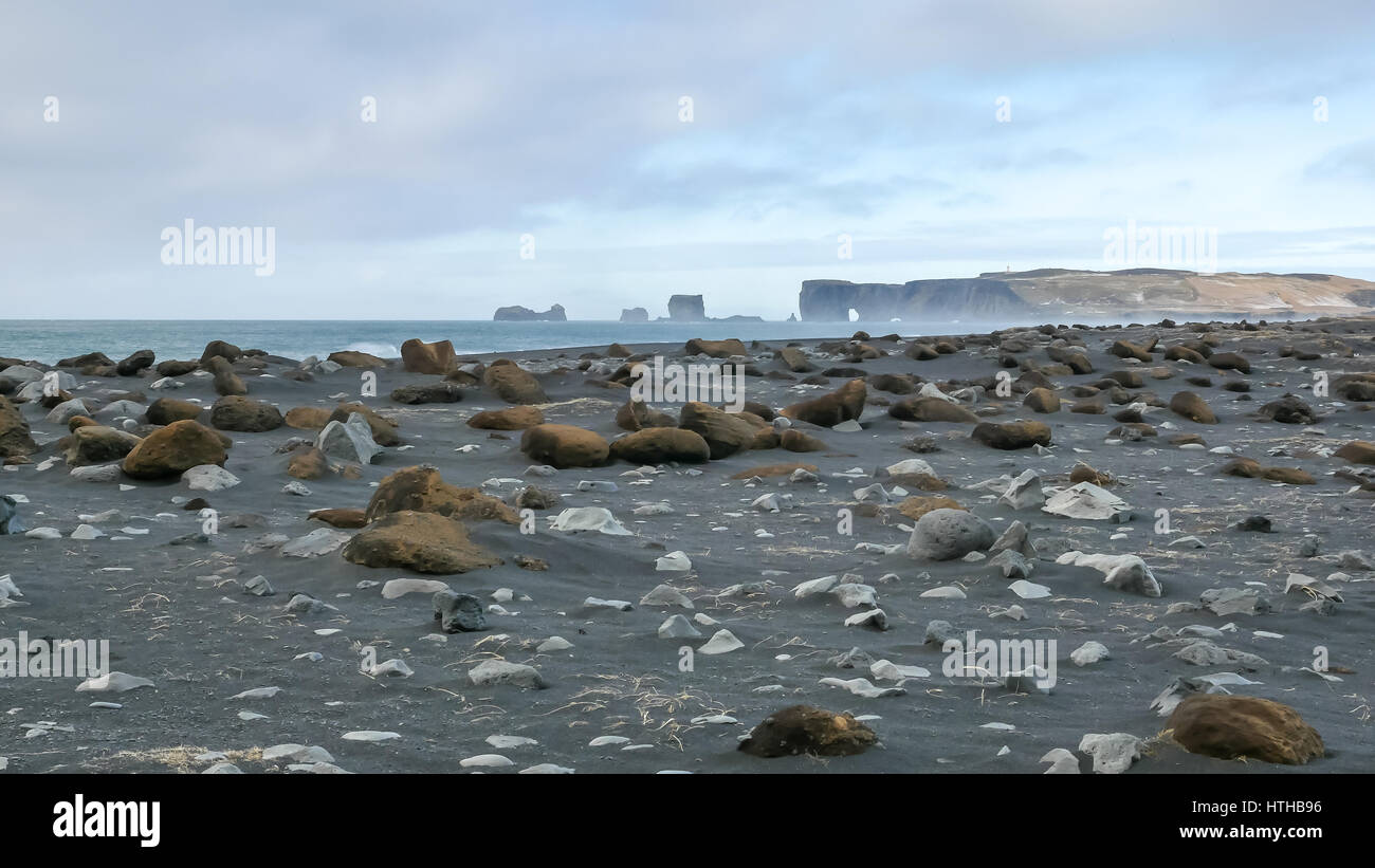 Reynisfjara spiaggia nera, Islanda, in luna giorno d'inverno senza persone con scogliere e scogli di mare in lontananza Foto Stock