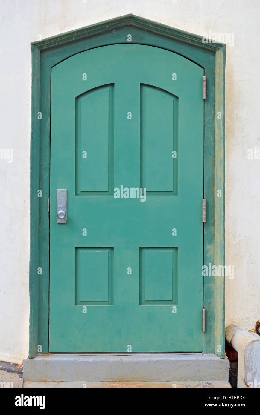Verde, metallo, porta ad arco in intonaco bianco muro di un edificio pubblico in California Foto Stock