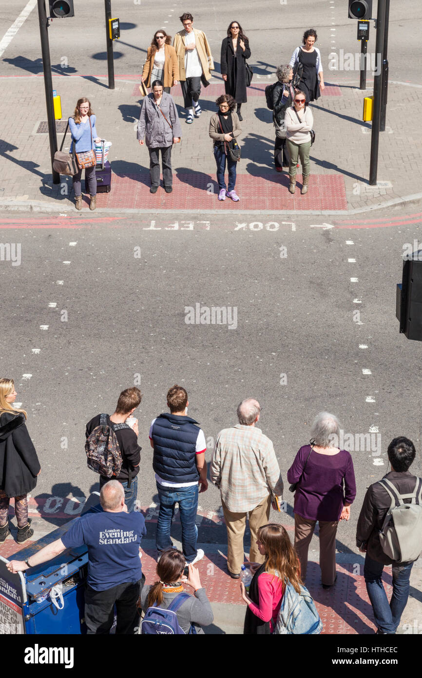 Le persone in attesa di attraversare la strada, London, England, Regno Unito Foto Stock