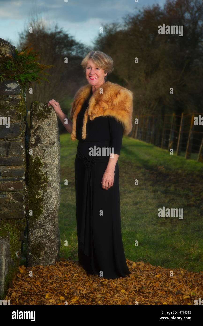 Donna di mezza età che indossa una pelliccia di volpe all'aperto nella campagna Foto Stock