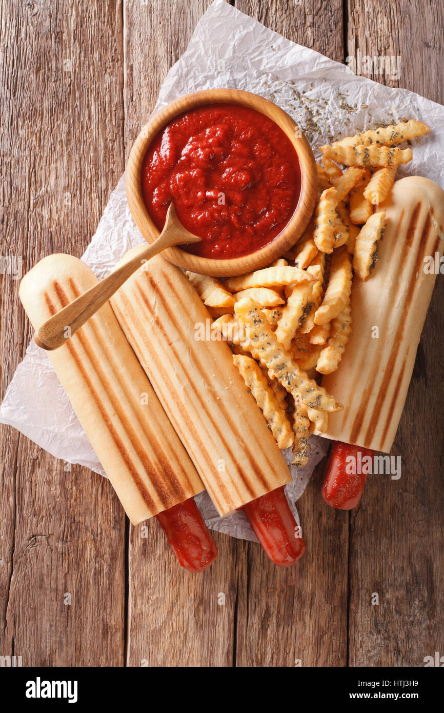 Il fast food: francese hot dog panini con patatine fritte e ketchup closeup sul tavolo. Vista verticale da sopra Foto Stock