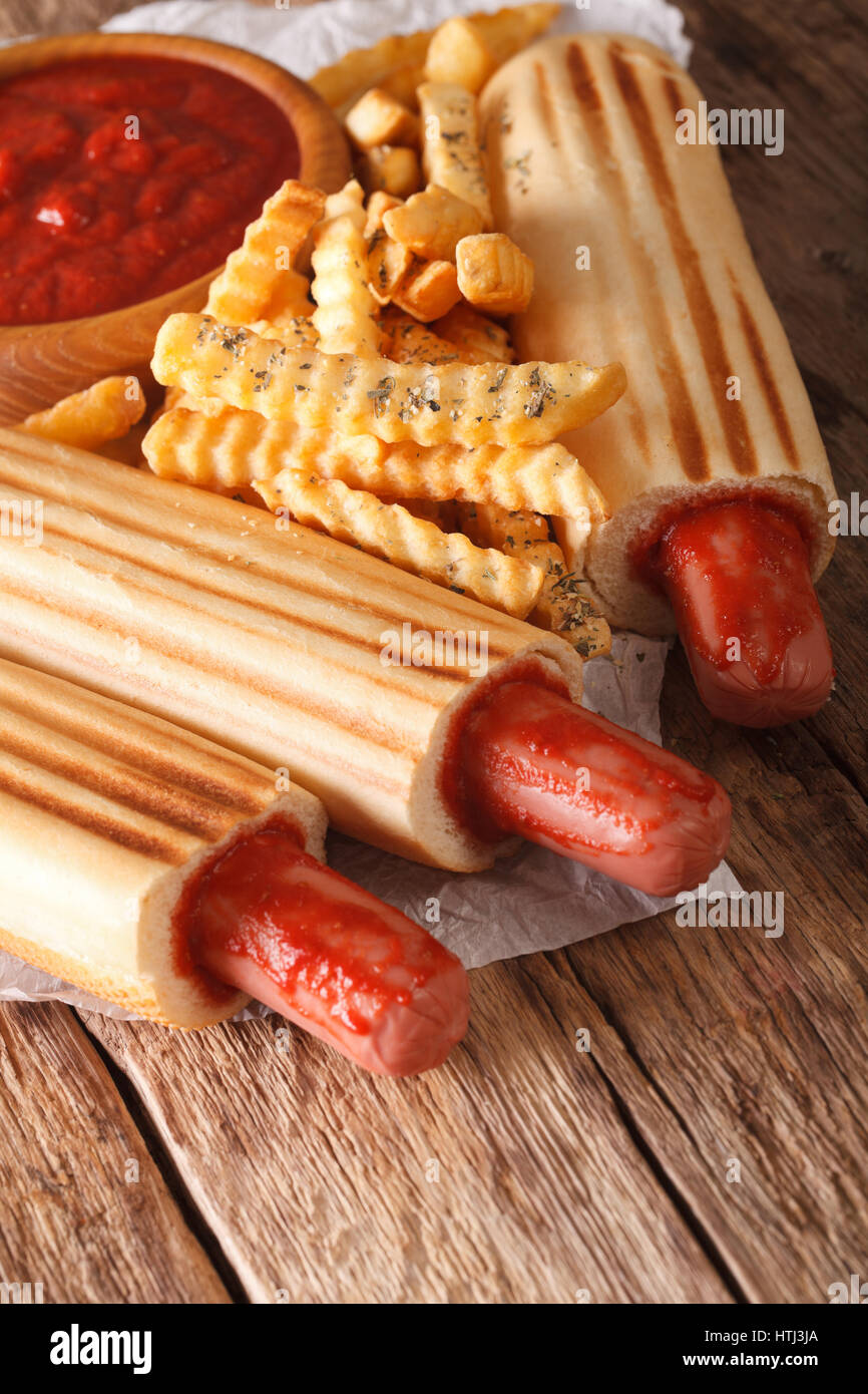 Il fast food: francese hot dog panini con patatine fritte e ketchup closeup sul piano verticale. Foto Stock