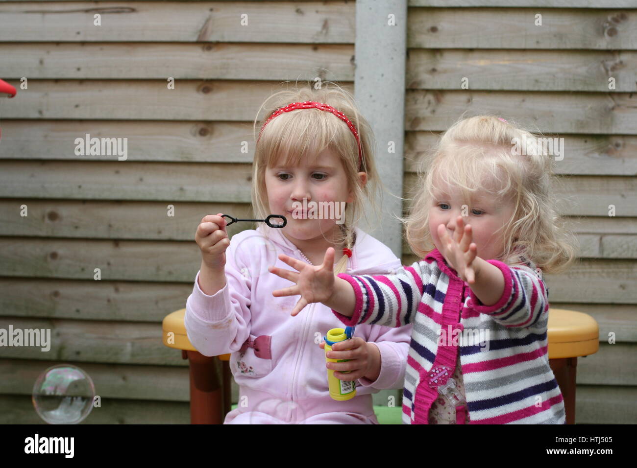 Bambini I bambini a soffiare bolle piccole bambine bionda sorelle giocando  scoppiare bolle bolla di sapone giardino meraviglia infantile awe e per il  divertimento di tutta la famiglia concept Foto stock -