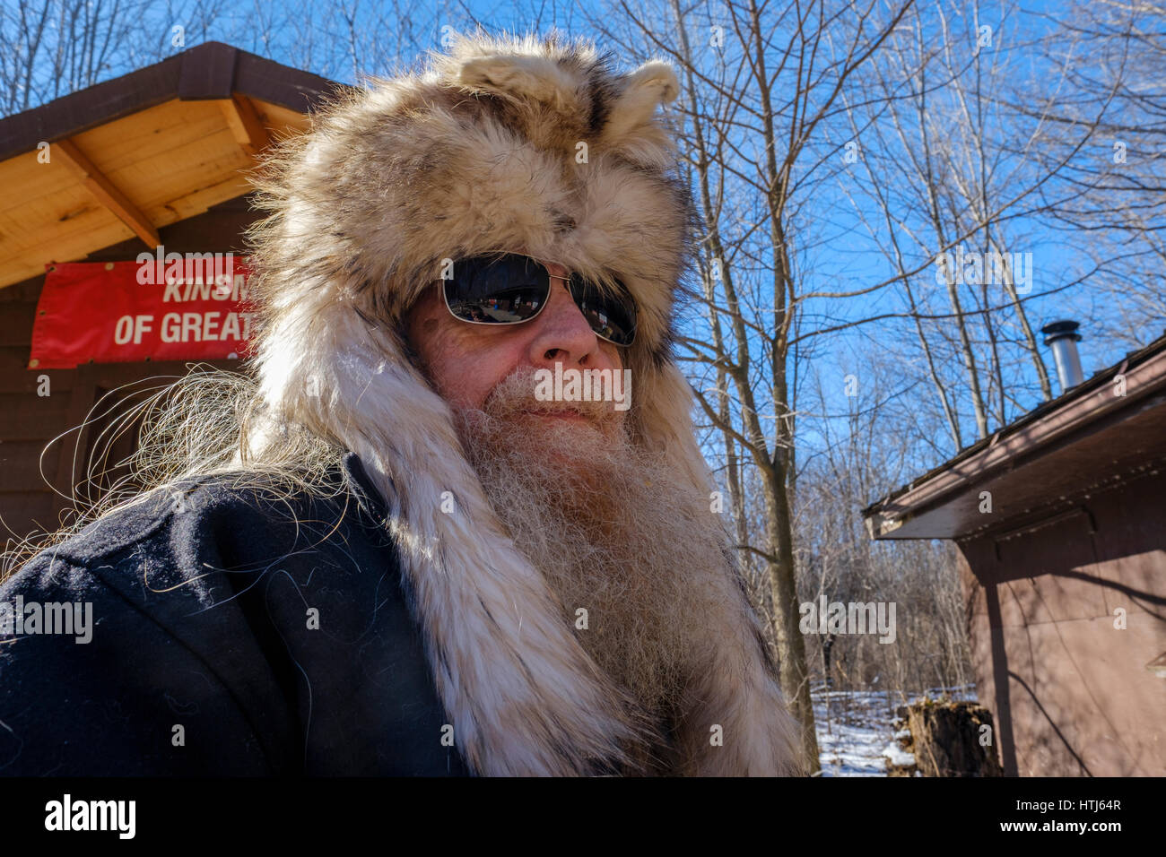 Uomo Barbuto, grigio barba e capelli grigi, uomo di mezza età che indossa coyote (Canis latrans) fur / pelt hat, ruvida cercando, a Londra, Ontario, Canada. Foto Stock