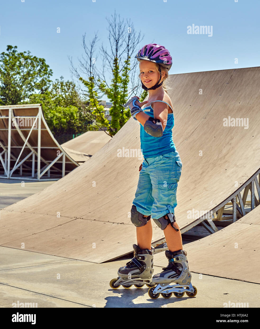 Ragazza roller skate casco walking park. Equitazione per bambini sui pattini a rotelle. Foto Stock