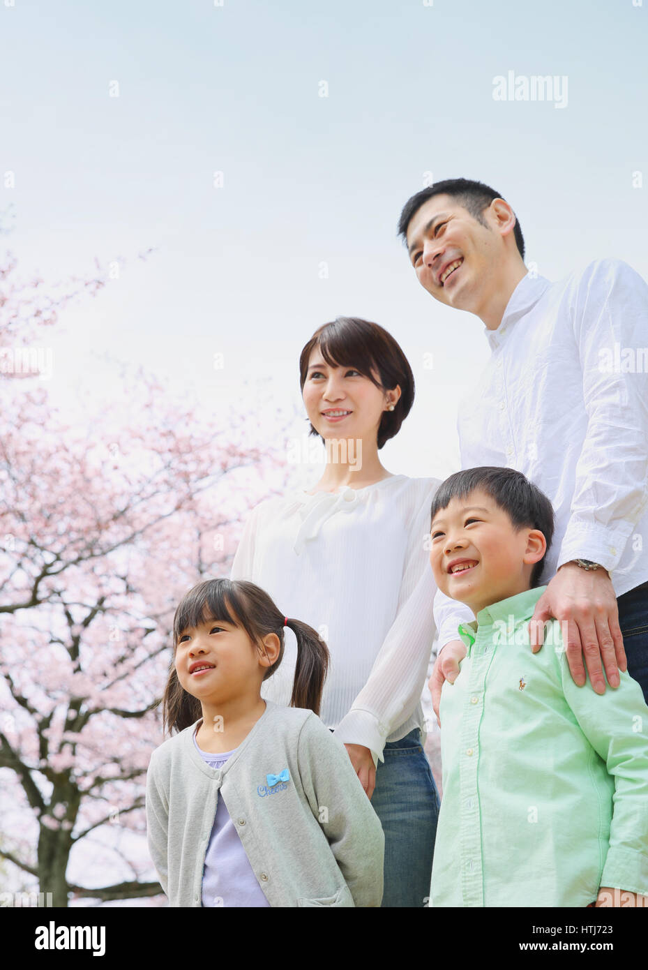 Famiglia giapponese con fiori di ciliegio in un parco della città Foto Stock