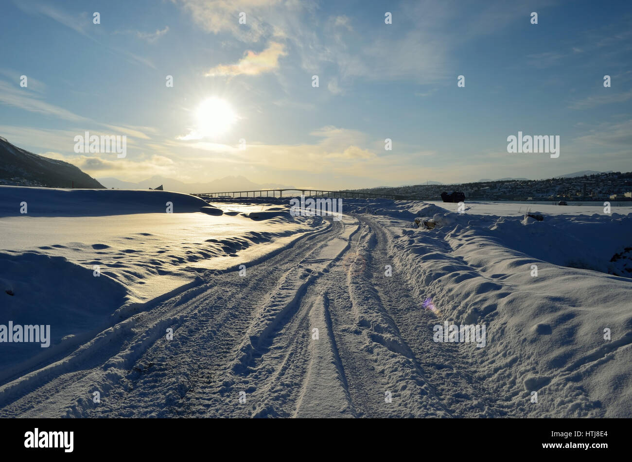 Strada innevata con tromsoe città isola in background all'alba con cielo blu Foto Stock