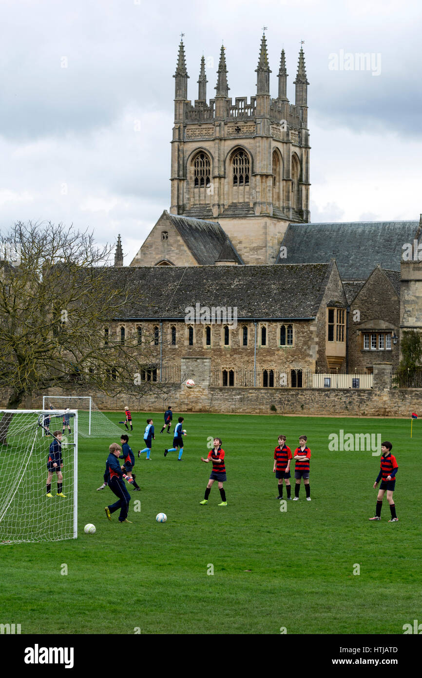 Merton College Chapel con scolari praticare calcio in primo piano, Oxford, Regno Unito Foto Stock