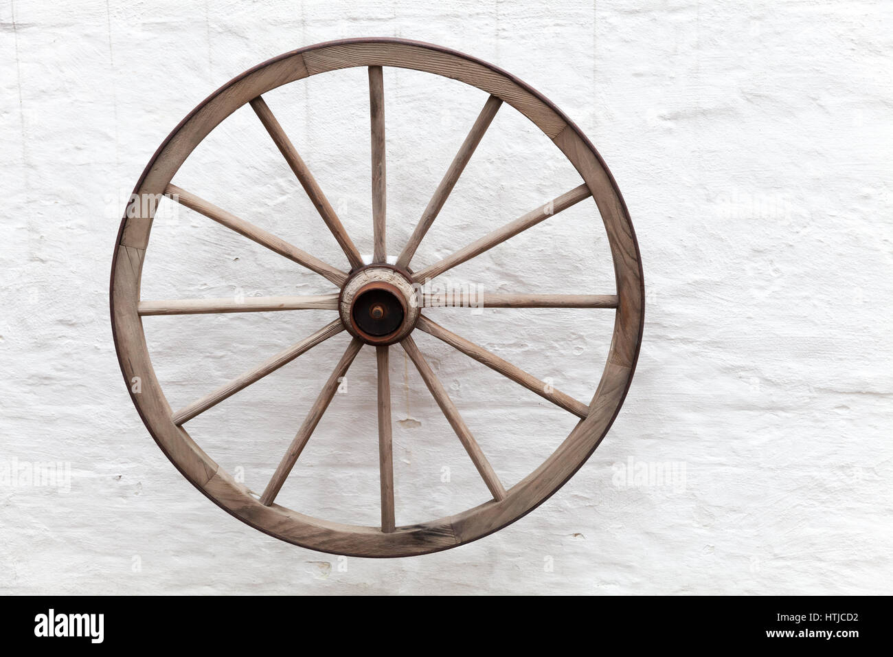 Vecchio carrello di legno ruota sospesa sul bianco parete rurale Foto Stock