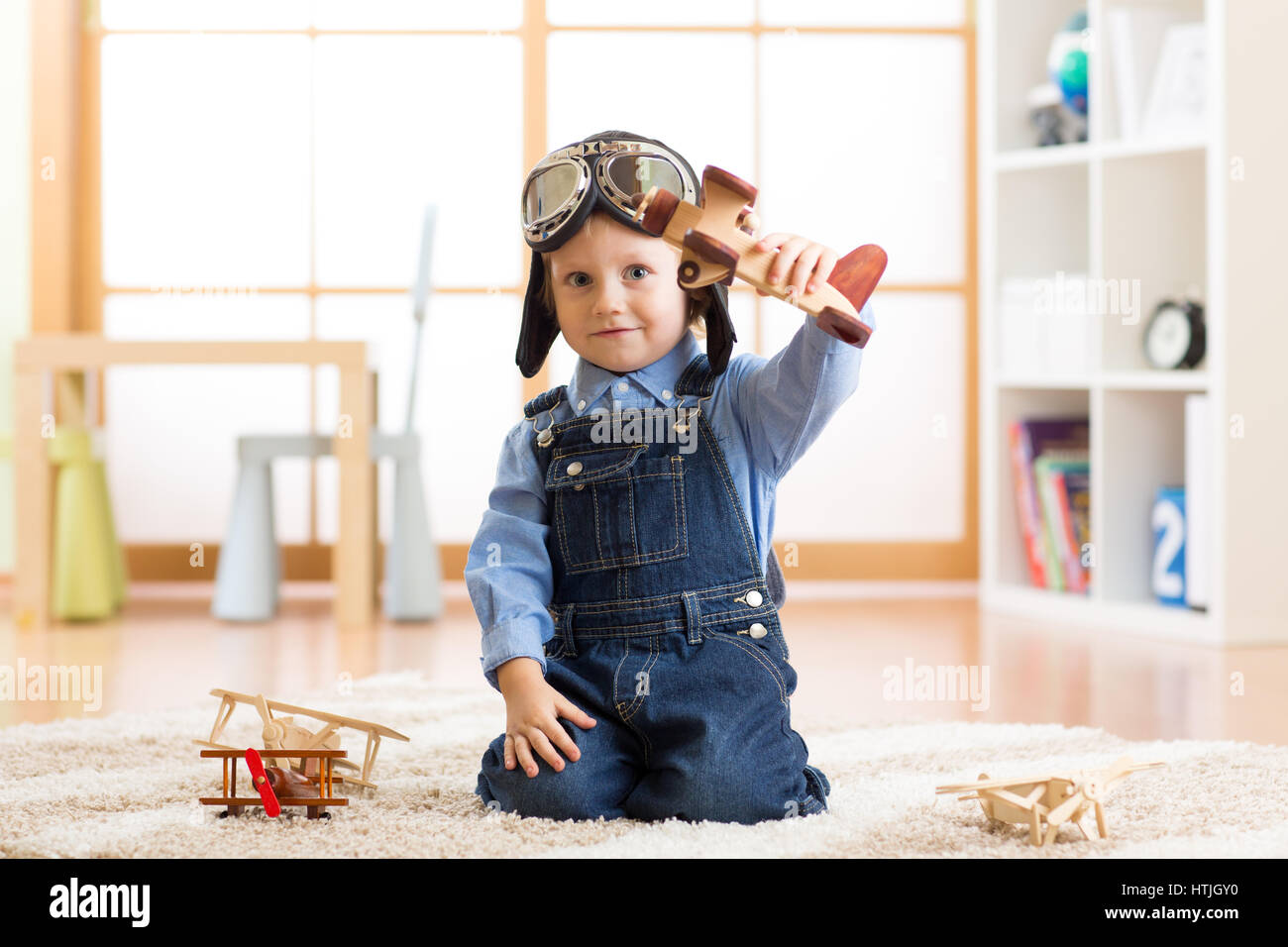 Bambino fingendo di essere aviatore. Kid giocando con gli aeroplani giocattolo a casa Foto Stock