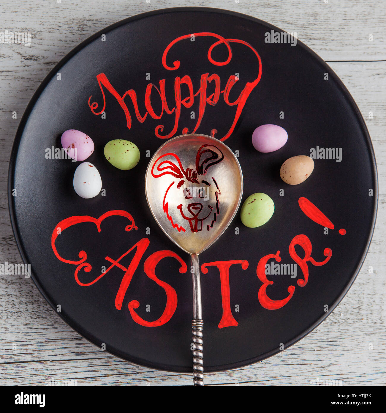 Felice Pasqua scritte a mano il preventivo scritto su piastra nera con il coniglietto di pasqua disegno su vintage cucchiaio d'argento. Immagine quadrata Foto Stock