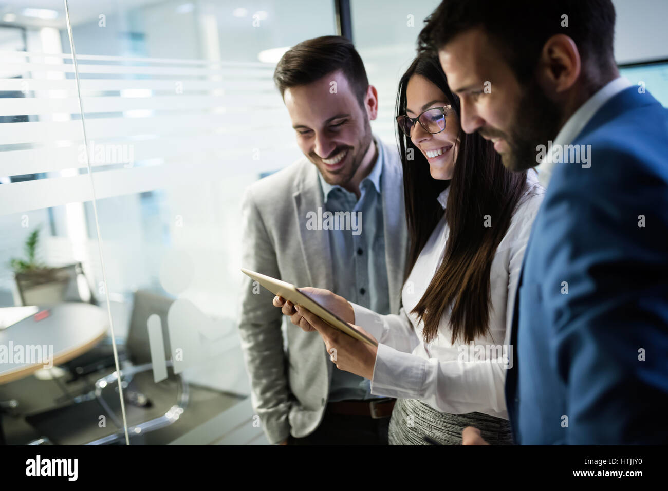Felice la gente di affari in ufficio guardando tablet Foto Stock