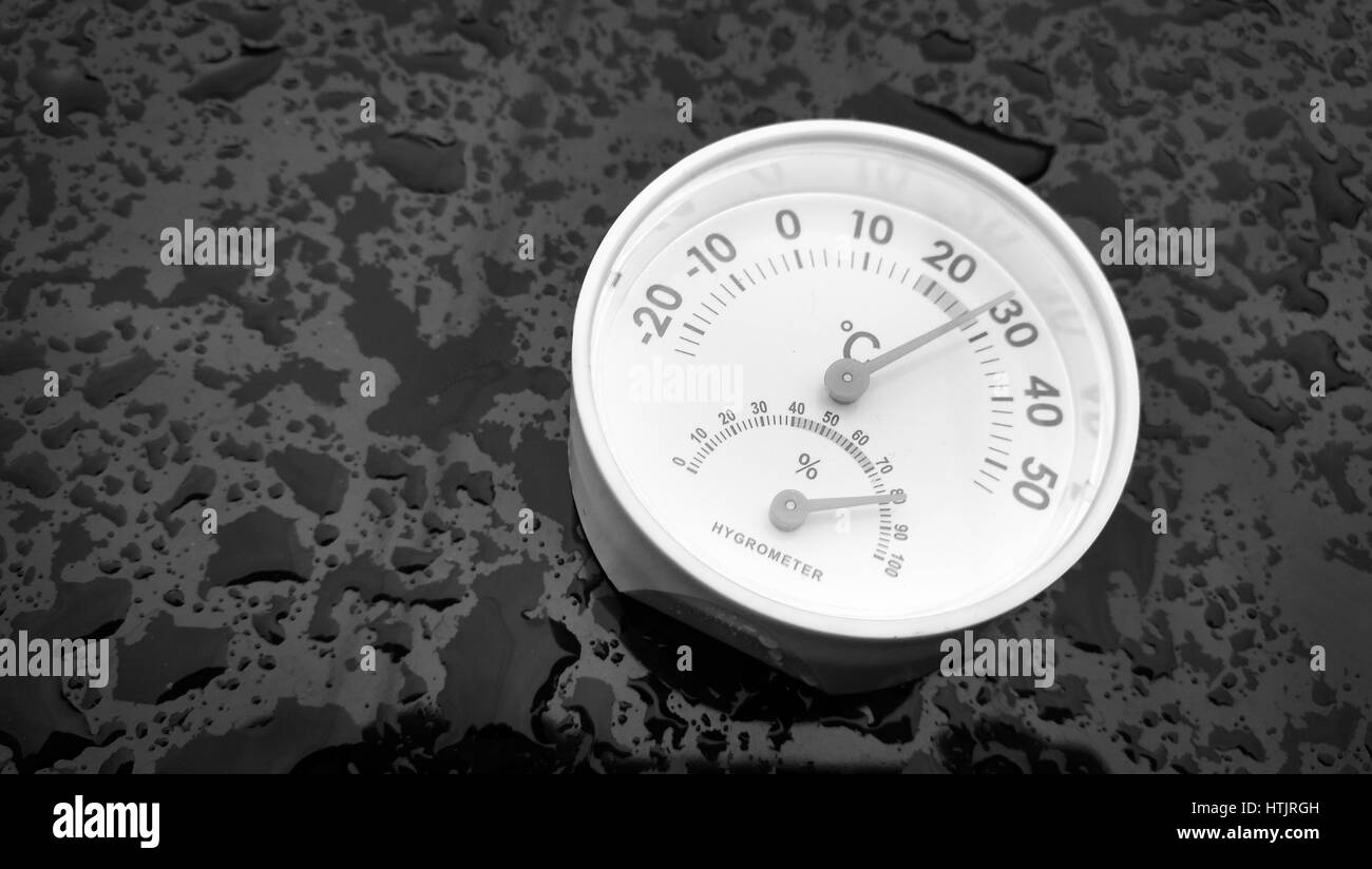 Igrometro analogico a mettere su uno sfondo nero riempito con goccia di acqua dopo la pioggia. Foto Stock