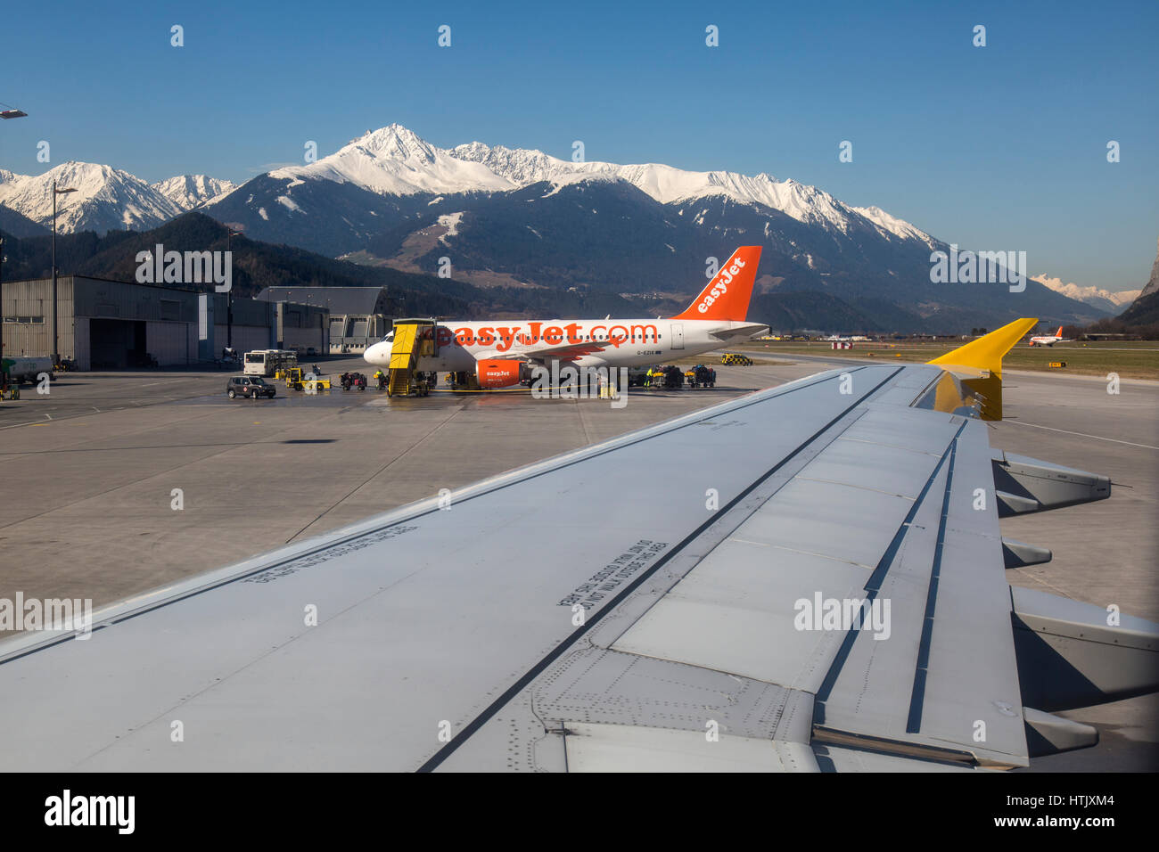Vista da una finestra di aeromobili all'aeroporto di Innsbruck, Austria. Montagne delle Alpi austriache in background e un Easyjet Airbus nel mezzo. Foto Stock